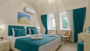 Une chambre d’h ôtel avec un grand lit, deux tables de chevet, une chaise, un bureau et une fenêtre avec des rideaux.