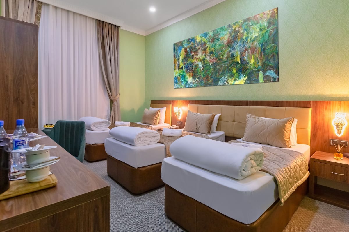 Ein Hotelzimmer mit zwei Betten, einem Schreibtisch und einem großen, abstrakten Gemälde an der Wand.