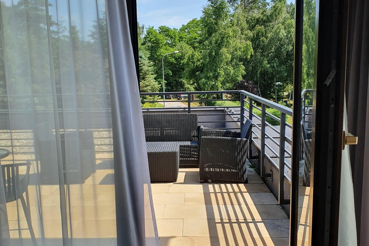 A balcony with wicker furniture and a view of trees and a road.