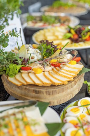 Buffet com diversos alimentos, incluindo pão fatiado, ovos e saladas.