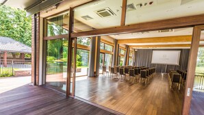 A conference room with a large screen, wooden flooring, and large windows.