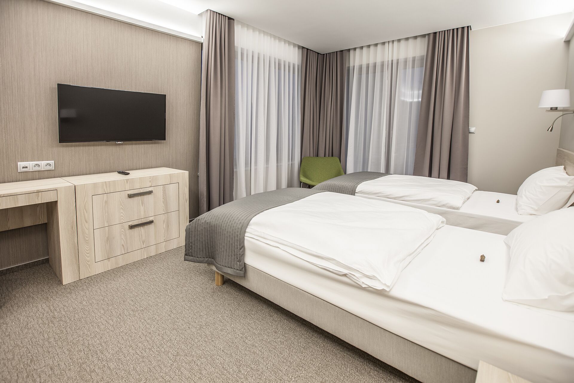 Una habitación de hotel con una cama, un escritorio, una silla y un televisor.