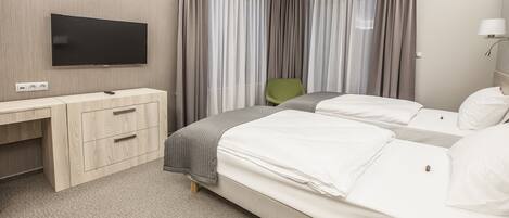 Una habitación de hotel con una cama, un escritorio, una silla y un televisor.