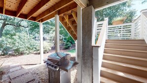 Ein überdachter Außenbereich mit Grill, Holzbalken und weißem Zaun.