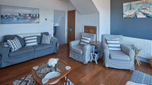 A living room with a sofa, armchairs, a coffee table, and artwork on the walls.