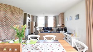Ett kompakt bostadsutrymme med en matplats, en soffa och en tv.