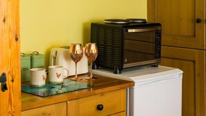 Uma cozinha com uma torradeira, duas taças de vinho e uma caneca de café sobre um balcão de madeira.
