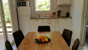 Eine kleine Küche mit Esstisch, Stühlen, Obstschale, Mikrowelle und Schränken.