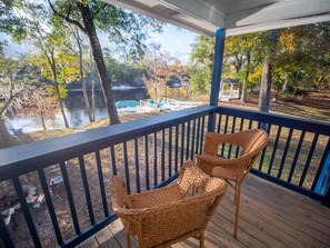 A wooden deck with wicker chairs, overlooking a lake and a gazebo.