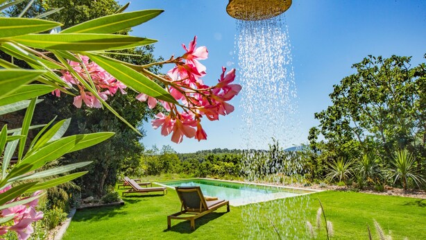 A poolside area with a clear view of the pool, surrounded by lush greenery and a wooden deck. - Bastide Saint-Estève (Brue-Auriac)