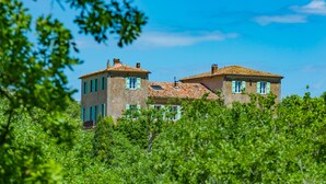 A two-story building with a tiled roof, surrounded by lush greenery. - Bastide Saint-Estève (Brue-Auriac)