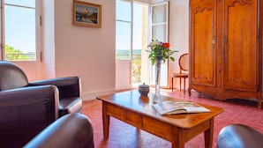 A room with a wooden table, two leather chairs, a vase with flowers, a book, and a wooden cabinet. - Bastide Saint-Estève (Brue-Auriac)