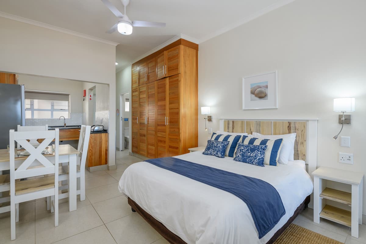 A bedroom with a bed, bedside table, and a wooden wardrobe.