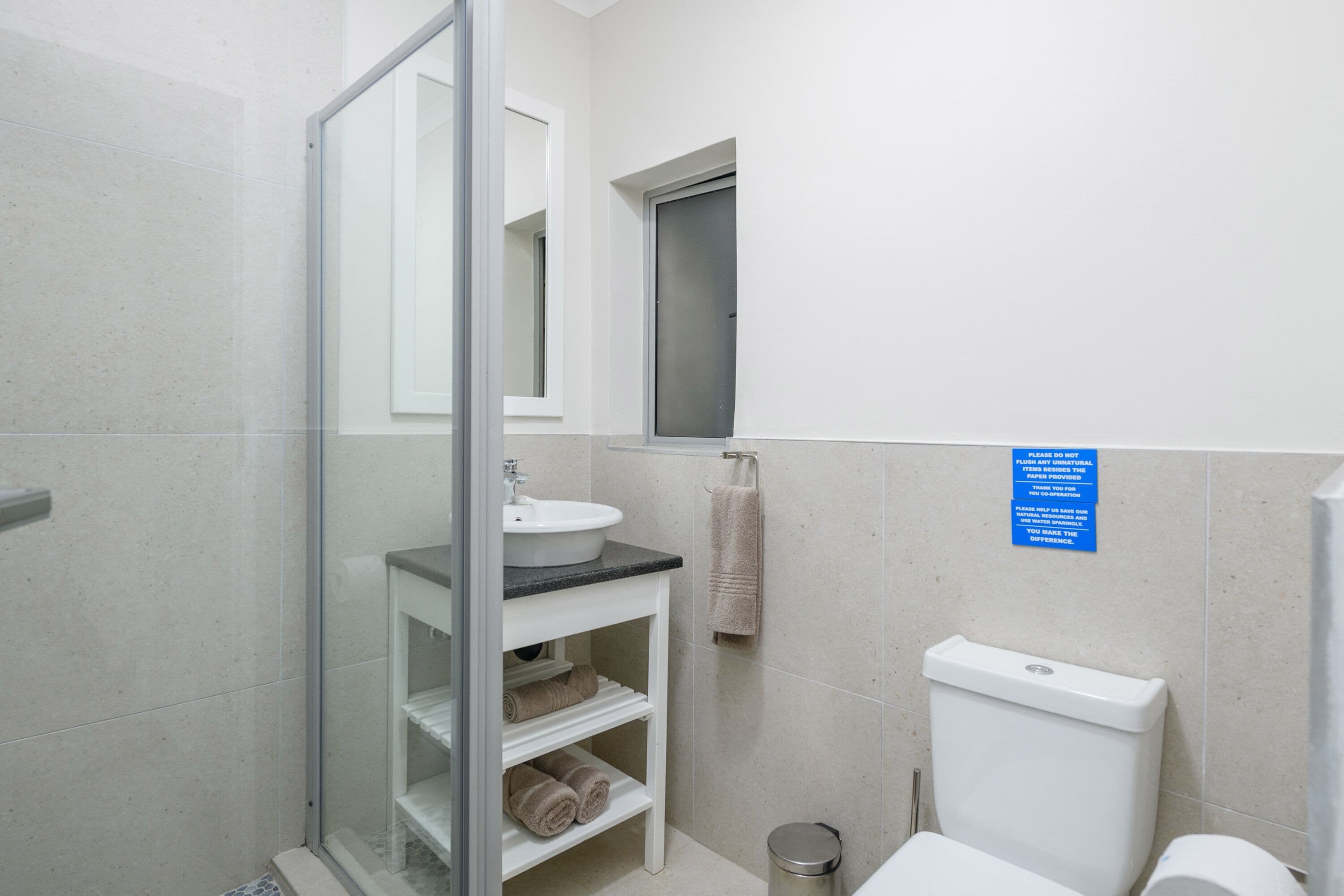 Un bagno con box doccia in vetro, lavandino, water e porta asciugamani.