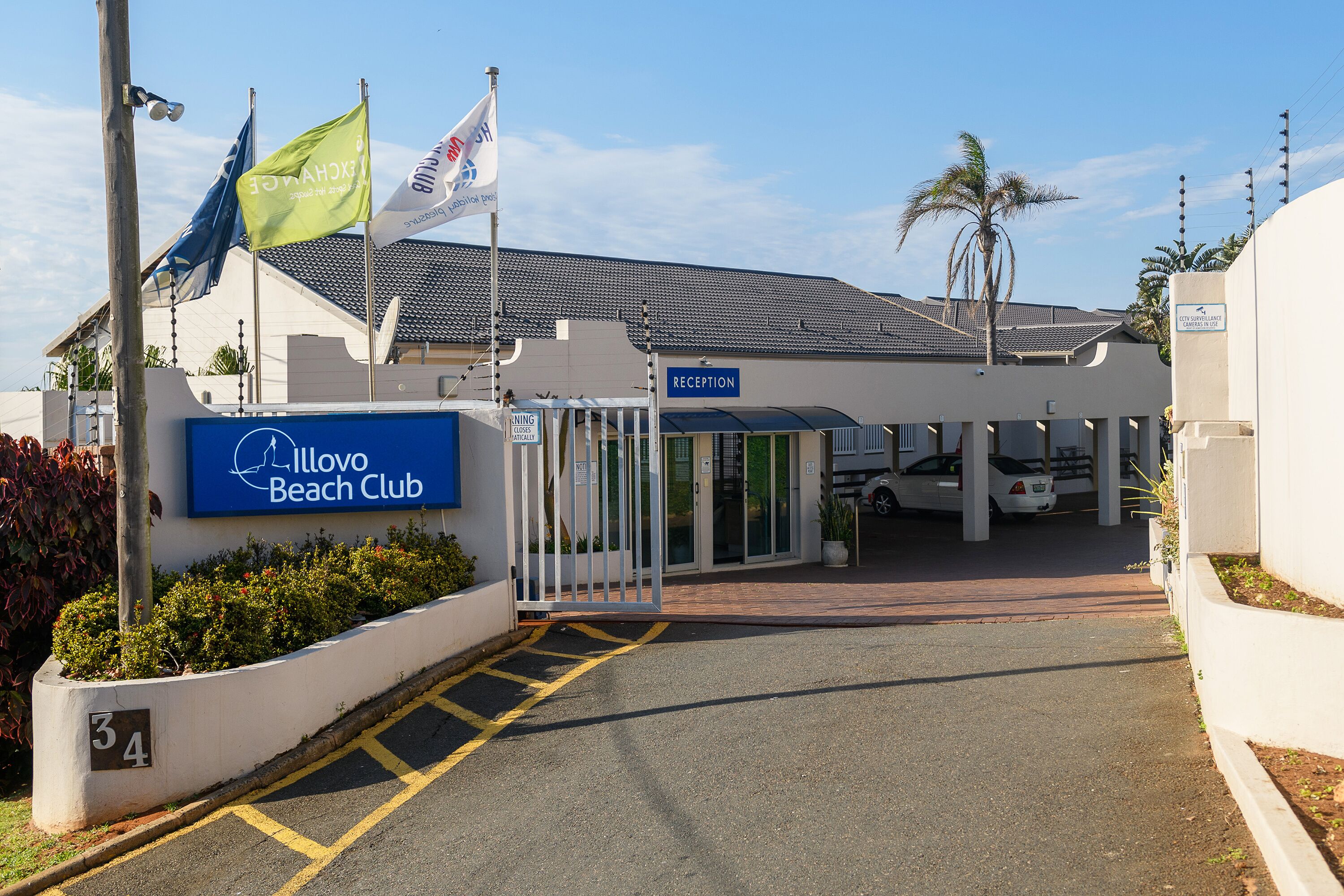 La entrada al Illovo Beach Club, con área de recepción, camino de acceso con puerta de seguridad y estacionamiento.