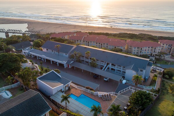 Een resort met een zwembad, meerdere gebouwen en uitzicht op het strand.