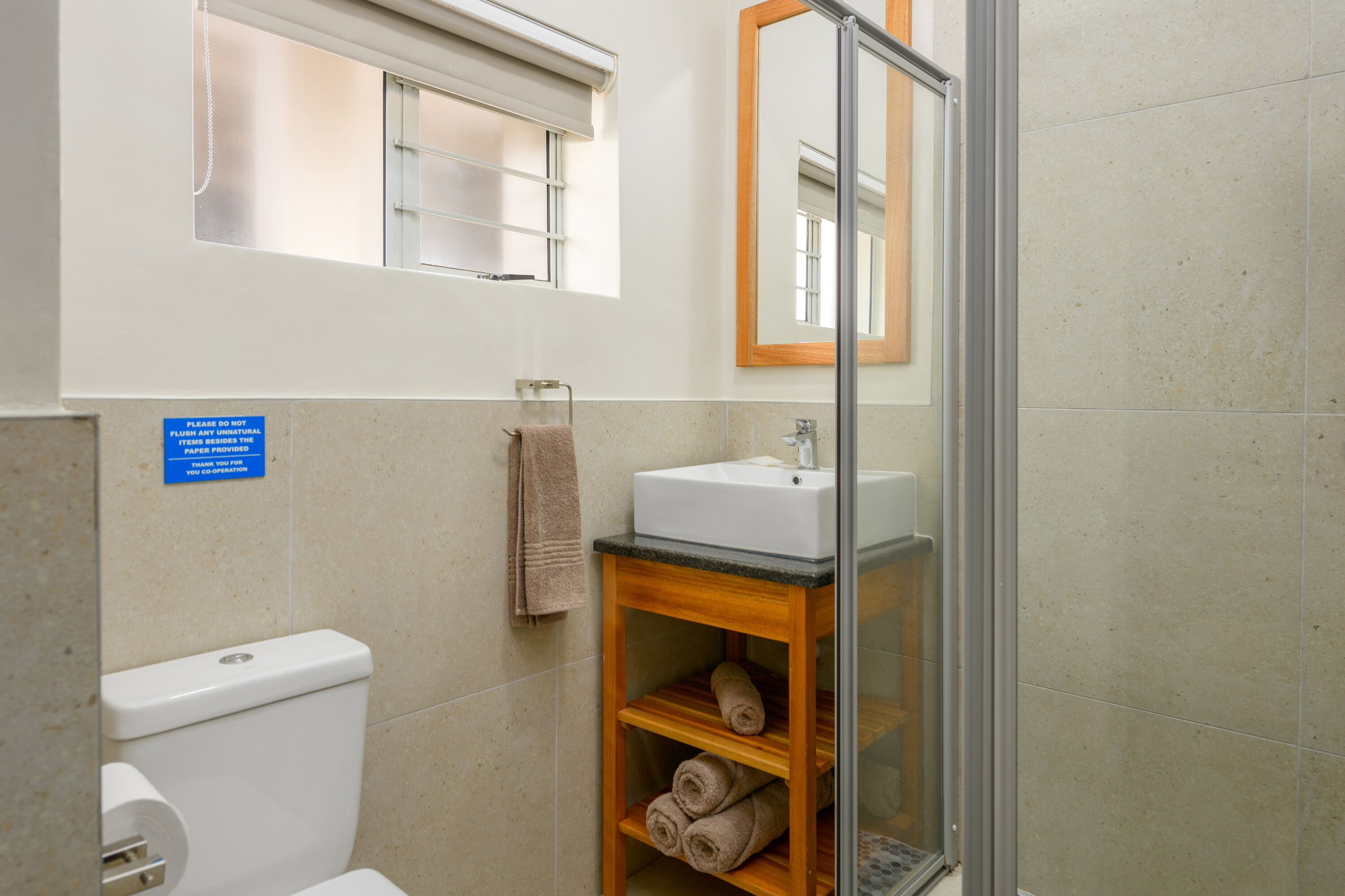 Une salle de bain équipée de toilettes, d’un lavabo et d’une douche à parois en verre.