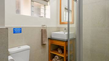 Une salle de bain équipée de toilettes, d’un lavabo et d’une douche à parois en verre.