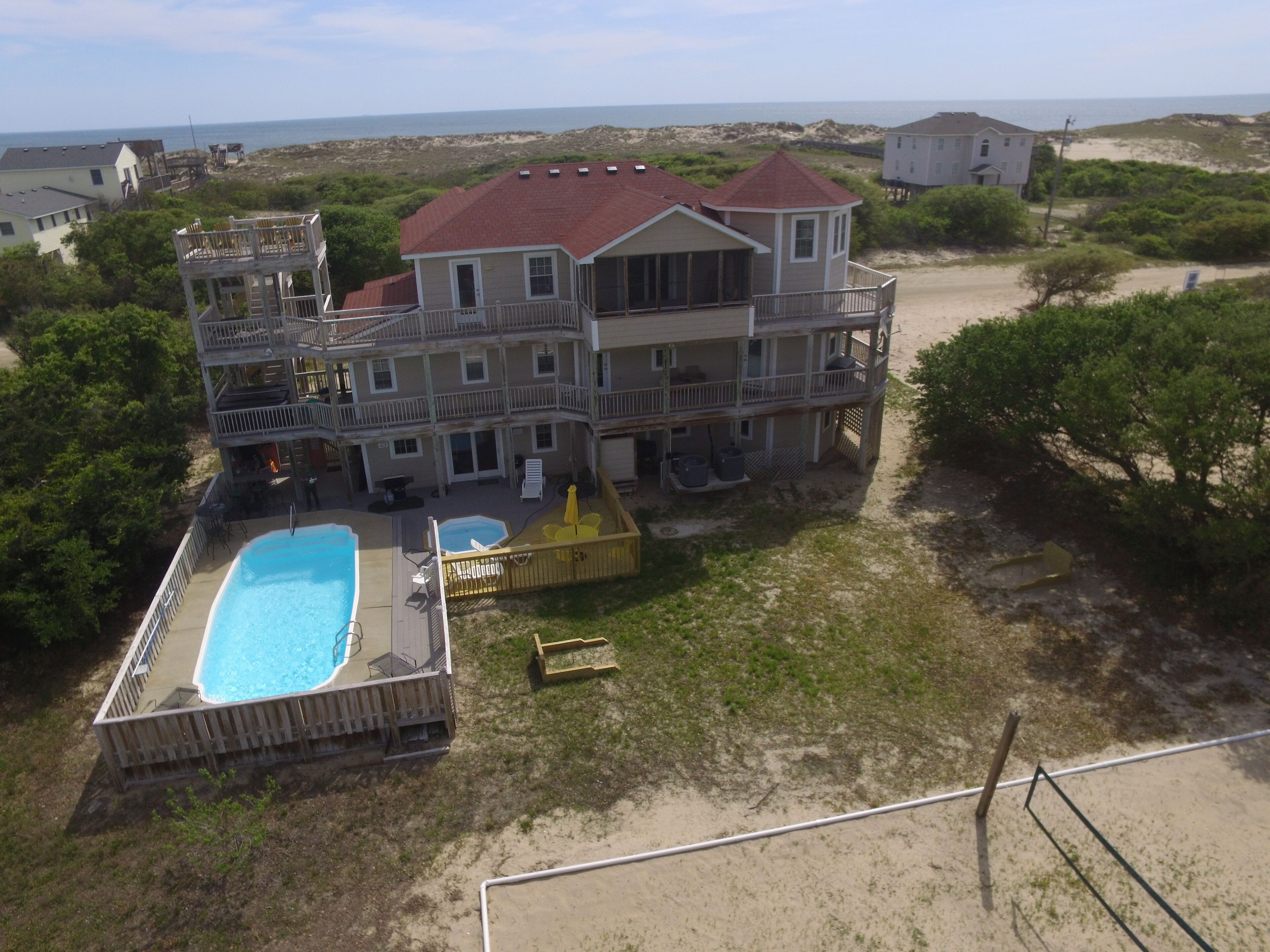 Una amplia casa de dos pisos con piscina, varios balcones y vista a la playa.