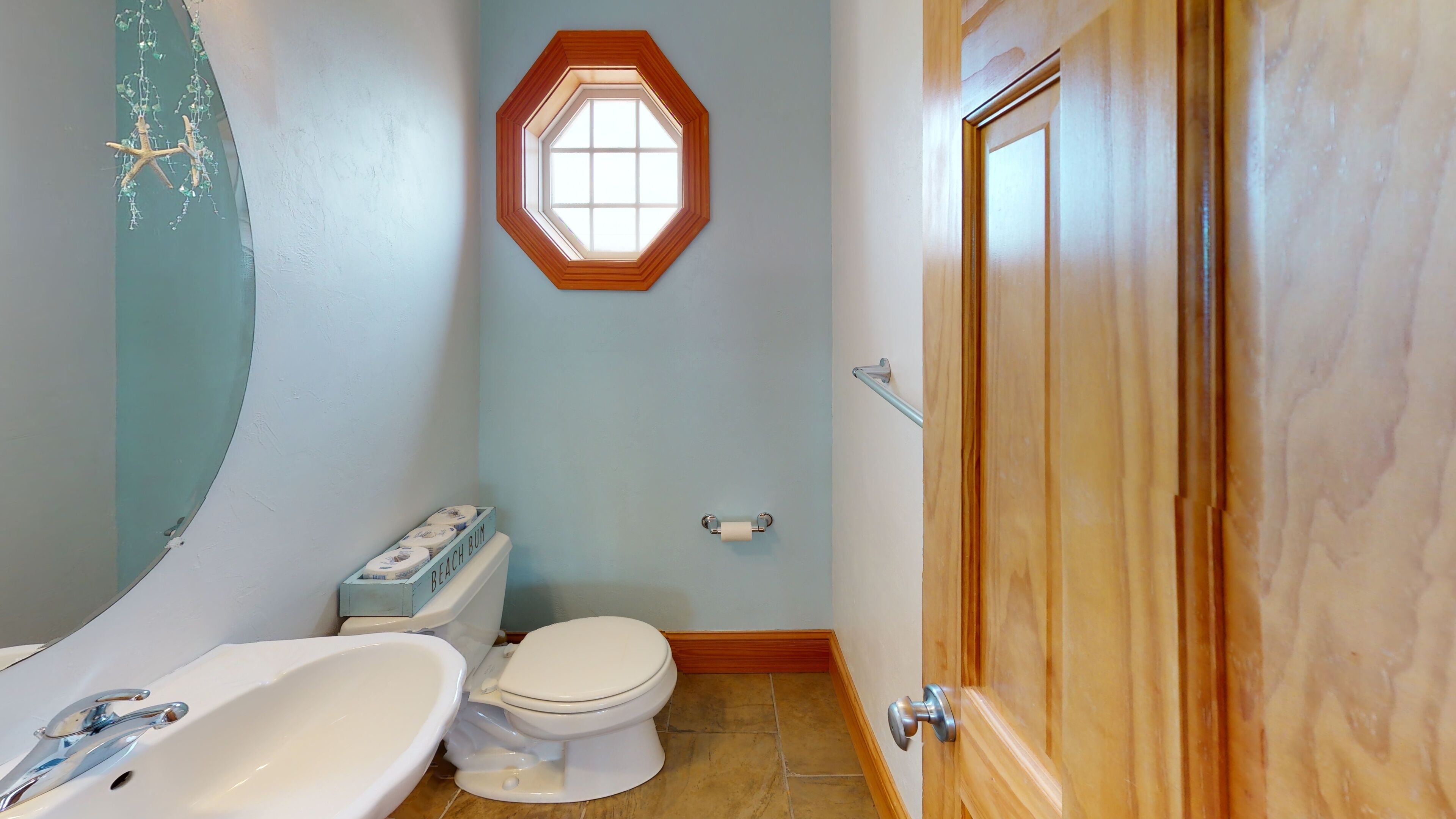 A bathroom with a bathtub, toilet, and a window with a wooden frame.