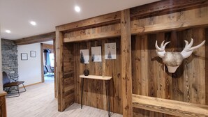 Un interior de madera con pared de piedra, techo de madera y un venado montado en la pared.