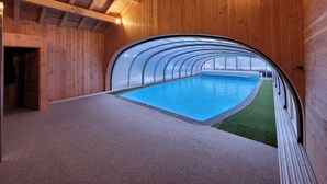Una piscina interior con revestimiento de madera y techo de cristal.