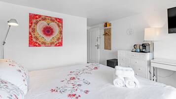 A hotel room with a bed, a desk, a wardrobe, and a wall-mounted artwork.