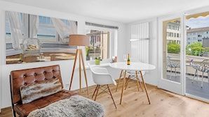 A modern living room with a large window, a dining table with chairs, a sofa, and a lamp. - HouseofHarmony (Stafa)