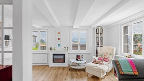 A bright living room with a fireplace, a bookshelf, and a cozy seating area. - HouseofHarmony (Stafa)