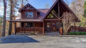 A log cabin with a porch, a front door, and a sign indicating it is a natural retreat.