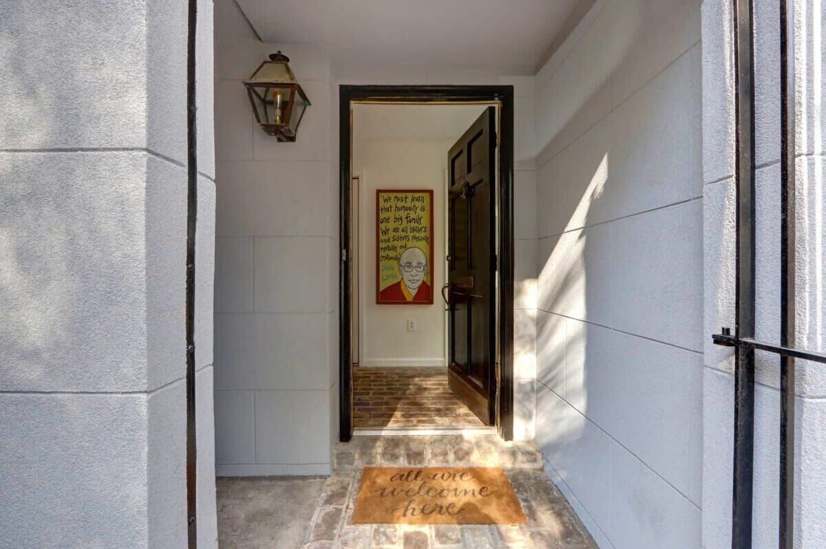 A hallway with a welcome mat, a door, and a poster on the wall.