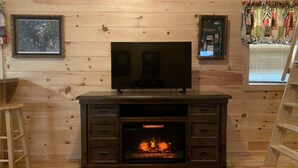 A wooden-paneled room with a fireplace, a TV mounted above it, and a ladder to the right.