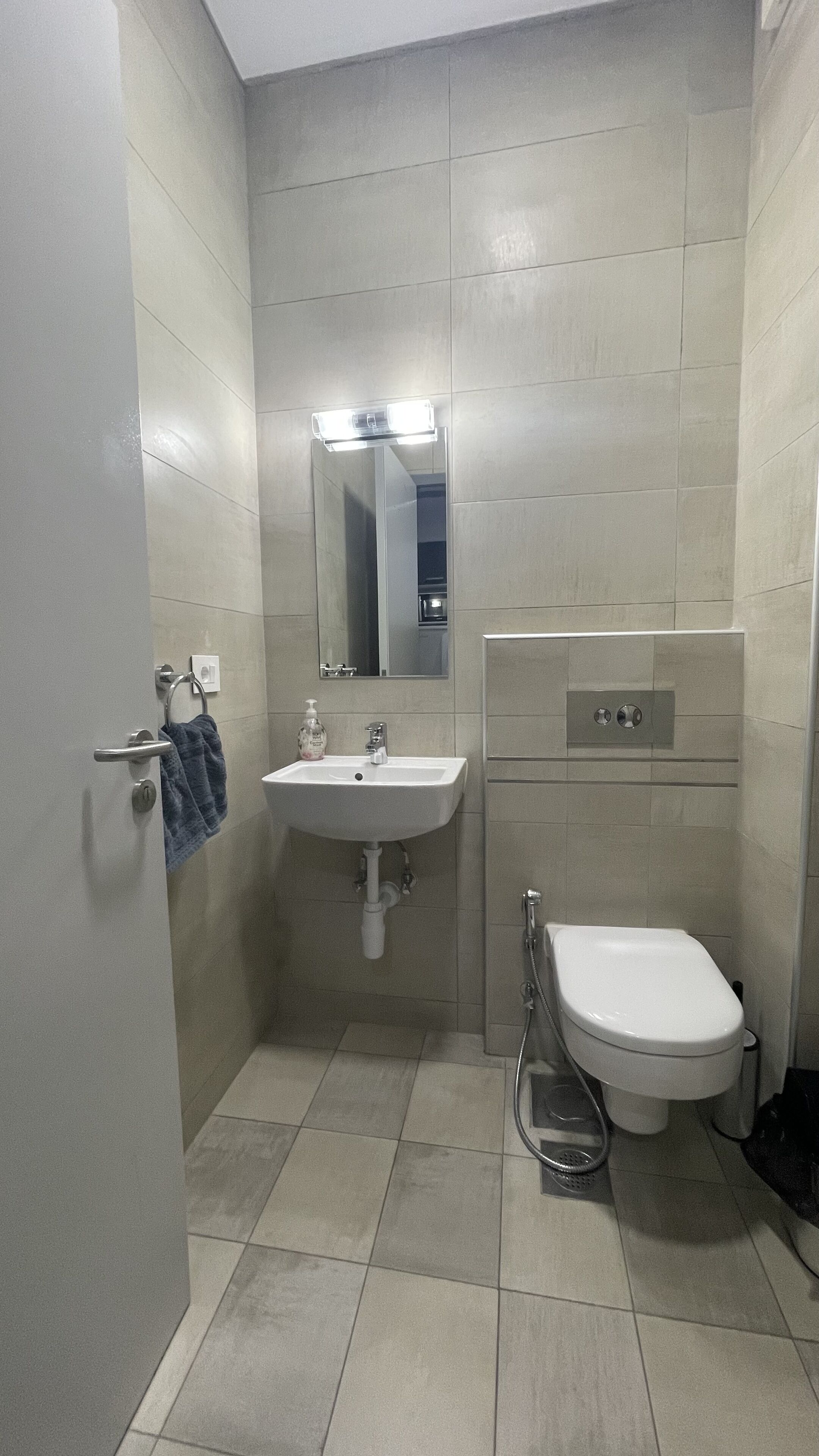 Un baño pequeño y moderno con lavamanos, espejo y retrete blancos.