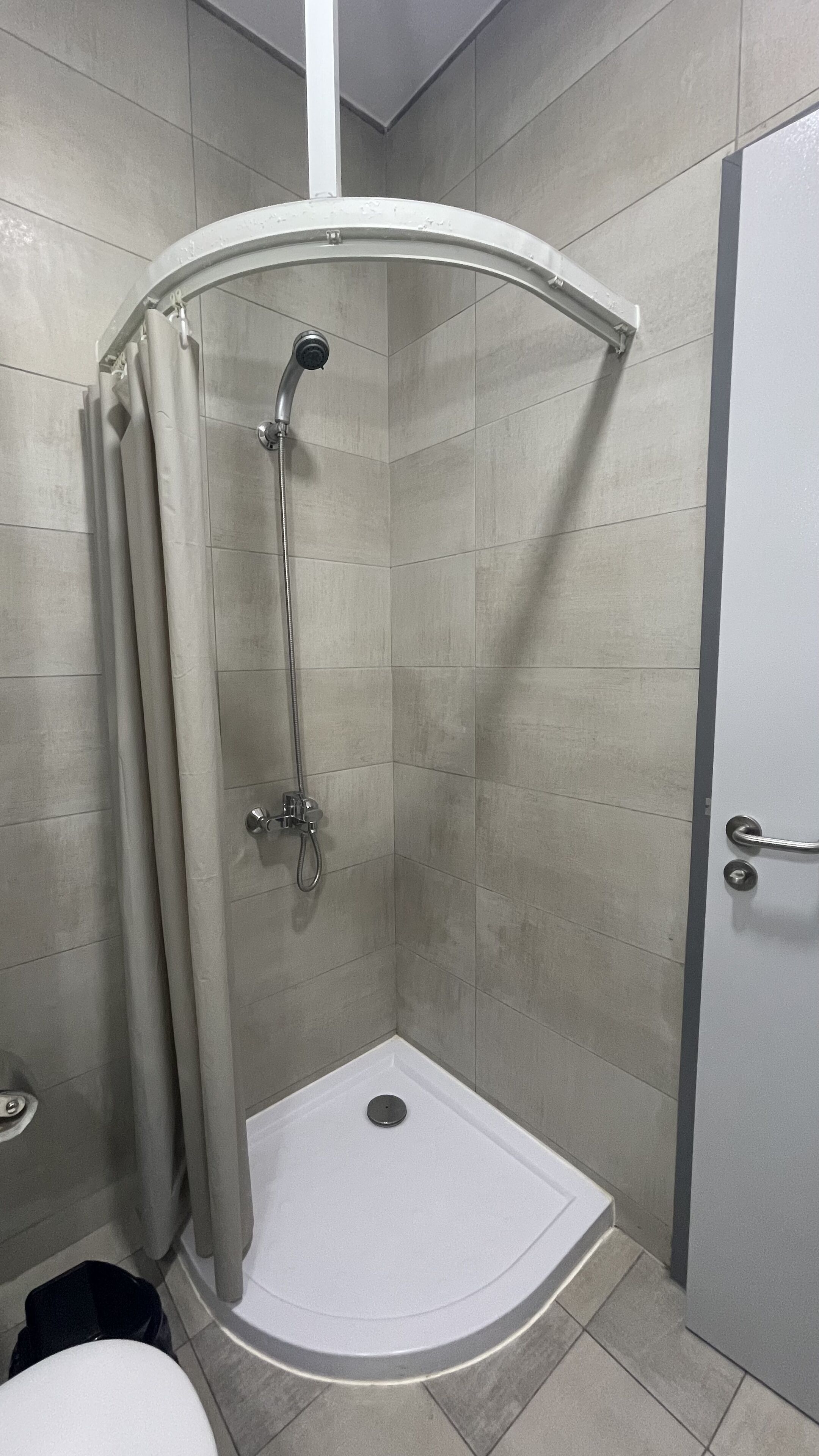 A modern bathroom with a shower enclosure, a toilet, and a door.