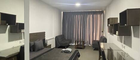 Una habitación de hotel con una cama, un escritorio, una silla y un televisor.