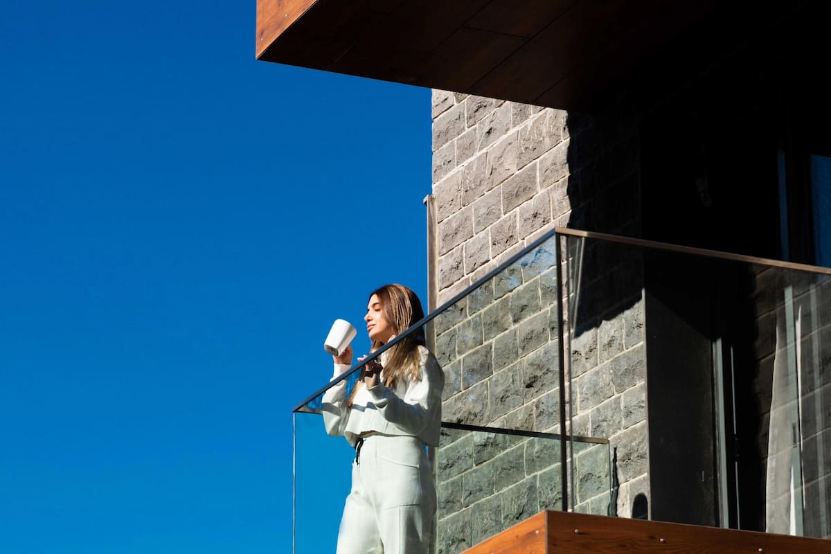 Eine Person befindet sich auf einem Balkon mit moderner Architektur, mit Holzausscheidungen und Glasgeländern.