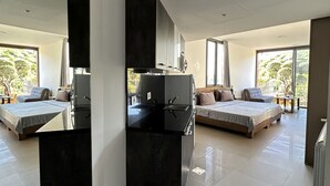 Een moderne, open woonkamer met keuken, twee slaapkamers en grote ramen voor natuurlijk licht.