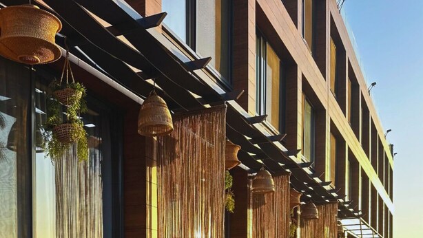 Een modern hotel met een zitgedeelte bij het zwembad, grote ramen en een helderblauw zwembad.