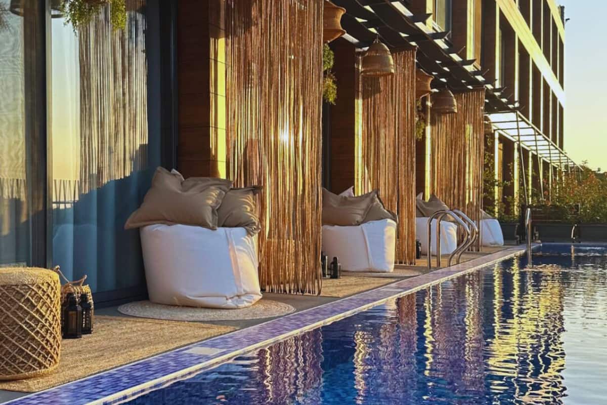 Ein modernes Hotel mit Sitzbereich am Pool, großen Fenstern und einem klaren, blauen Pool.