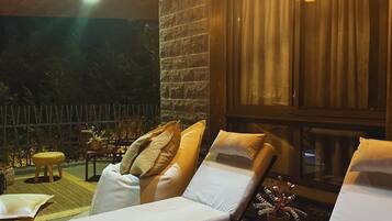 A lounge area with two reclining chairs, a stone wall, and a window with curtains.