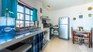Una cocina moderna con un dispensador de agua grande, un refrigerador y un comedor con sillas y una mesa de madera.