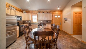 Una cocina amplia con armarios de madera, un refrigerador de acero inoxidable y una zona de comedor con una mesa redonda y sillas.
