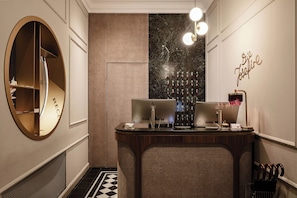 A hotel reception area with a reception desk, a wall-mounted wine cooler, and a decorative wall sign. - Eurostars Josefine (Vienna)