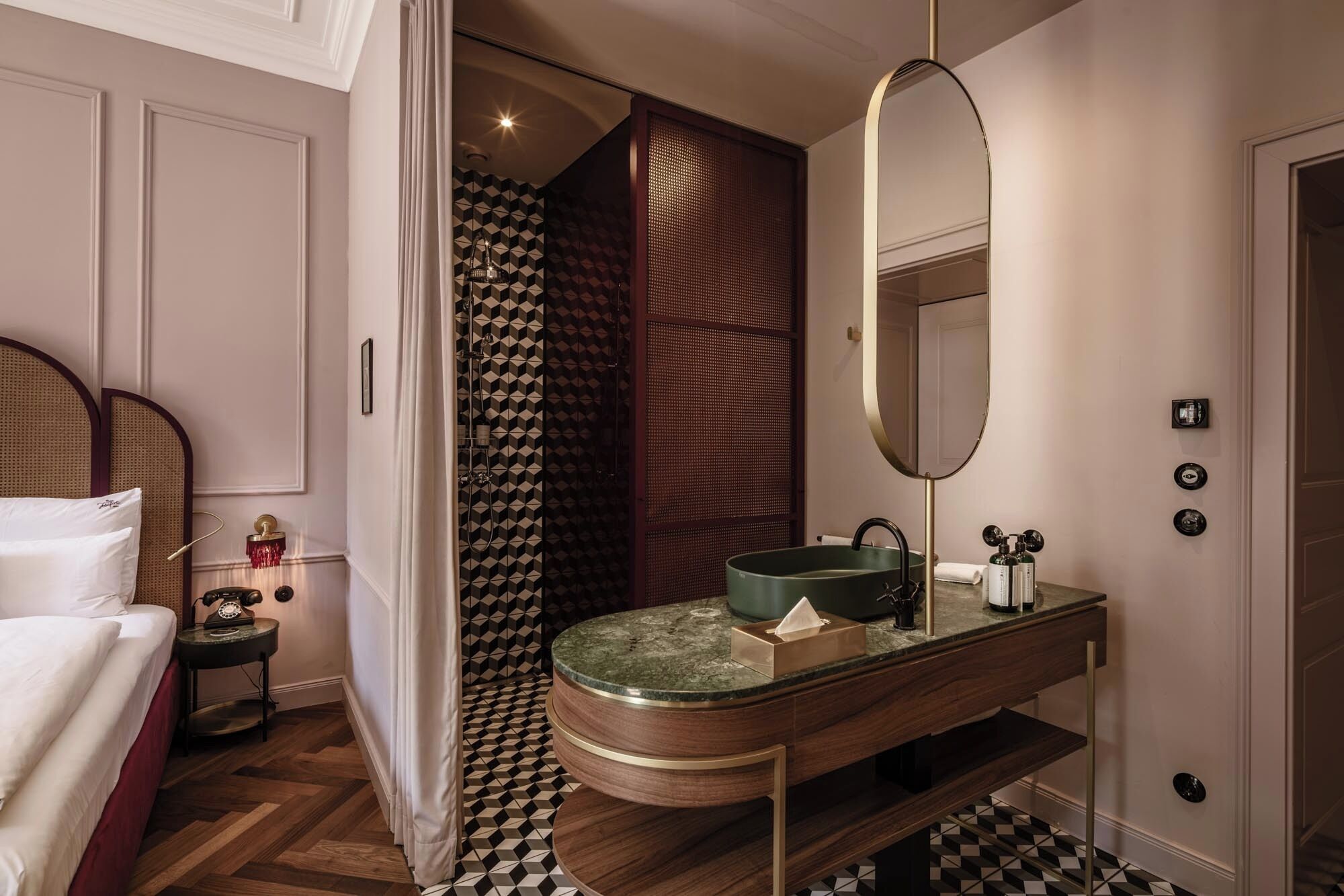 A bathroom with a round sink, a mirror, and a shower with patterned tiles.