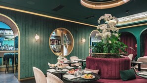 A restaurant interior with round tables, chairs, and a central floral arrangement. - Eurostars Josefine (Vienna)