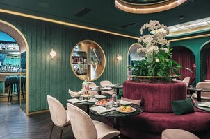 Een restaurantinterieur met ronde tafels, stoelen en een bloemstuk in het midden.
