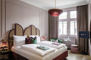 A hotel room with a large bed, a television, a desk, and a window with curtains. - Eurostars Josefine (Vienna)