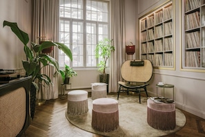 A cozy room with a large window, a bookshelf, and a rattan chair. - Eurostars Josefine (Vienna)