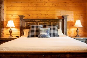 Ein Zimmer mit Holzwänden, einem Bett, zwei Nachttischen und zwei Lampen.