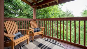 Eine Holzterrasse mit zwei Adirondack-Stühlen und einer karierten Decke.